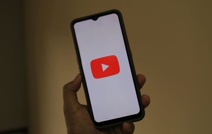 Close-up of a smartphone displaying the YouTube app logo on the screen.